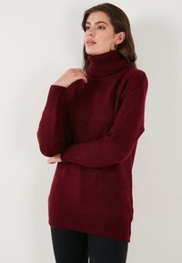 Burgundský rolák s textúrovaným pletením, ribbed manžetami a lemom. Oversized strih s uvoľnenou siluetou a dlhými rukávmi.