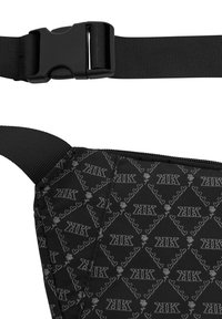 Čierna crossbody taška s opakujúcim sa motívom srdiečok a ruží. Nastaviteľný popruh s čiernou plastovou sponou. Hladká textúra.