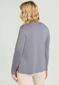 Graues Langarmoberteil mit rundem Halsausschnitt, glatter Textur, seitlichen Schlitzen und normaler Passform, von hinten betrachtet.