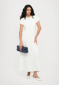 Abito maxi bianco, aderente, a maniche corte con tessuto morbido. Abbinato a una pochette blu navy e tacchi bianchi appuntiti.