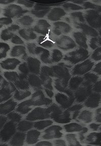 Ύφασμα με μοτίβο λεοπάρ σε μαύρο και γκρι, με μικρό λευκό λογότυπο Jumpman στο κέντρο.