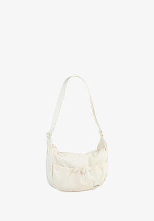 Cream-colored fabric shoulder bag with a gathered design, adjustable strap, and drawstring closure. Features a small logo tag on the front.