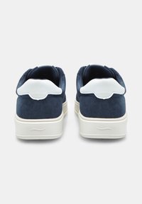 Tumesuede kingad valgete nahast kannatugedega ja tekstureeritud kummitaldadega, tagakülje vaade, mis tõstab esile kuju ja õmbluste detailid.