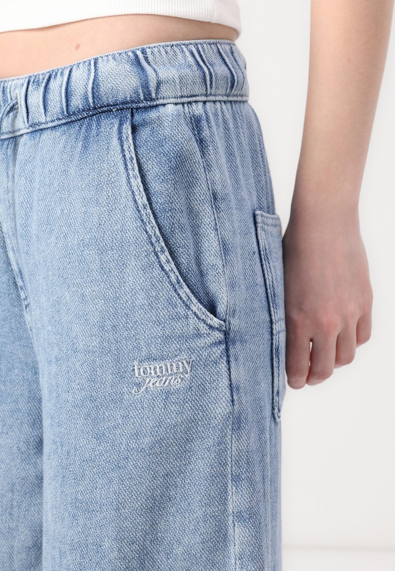 Jasnoniebieskie dżinsowe joggery z elastycznym pasem, bocznymi kieszeniami i małym haftowanym logo "tommy jeans" z przodu.