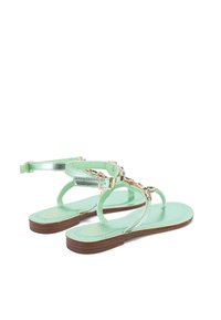 Sandali verde menta con cinturini metallici, suola piatta marrone e dettagli in hardware tono oro; design open-toe.