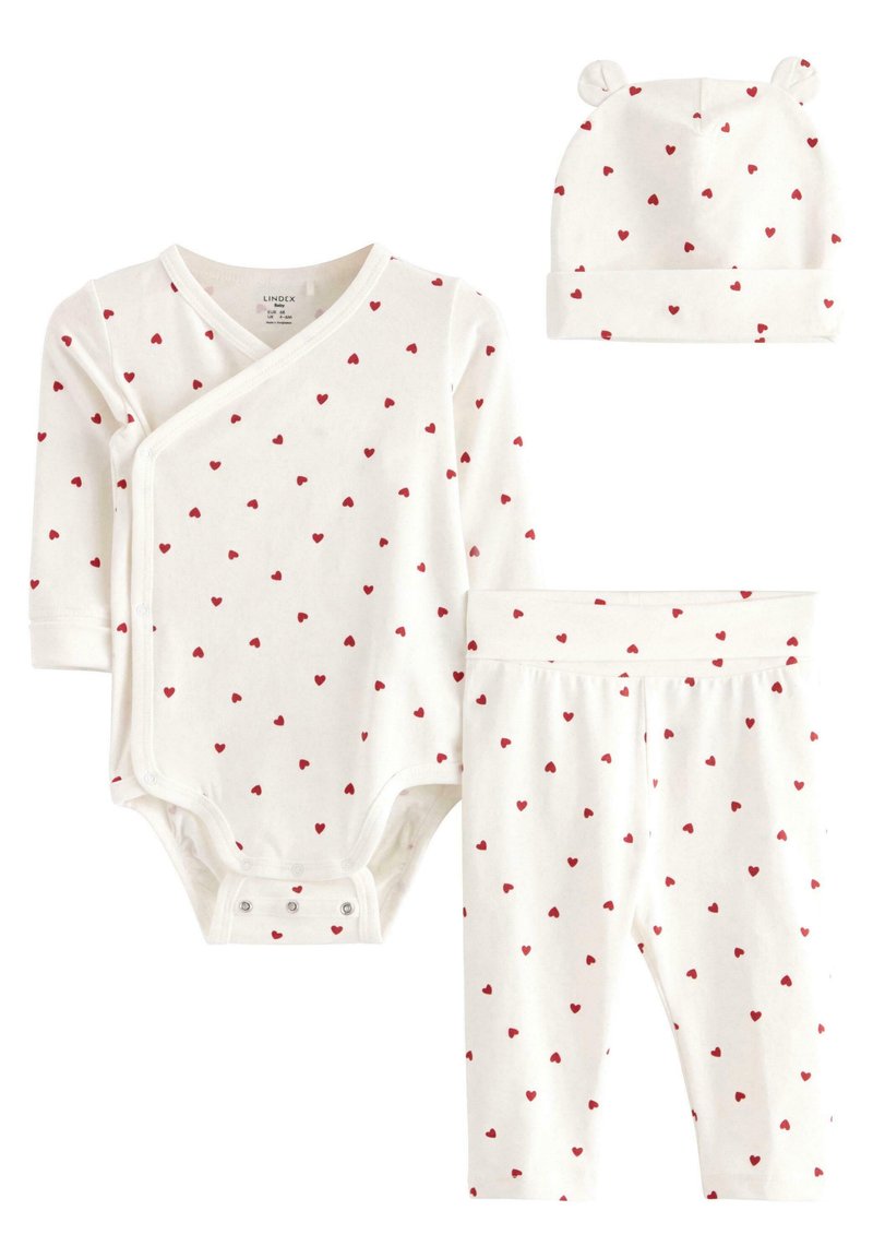 Ensemble pour bébé trois pièces comprenant un body blanc et un legging avec des motifs de cœurs rouges, ainsi qu'un bonnet assorti avec des oreilles d'ours. Matériau en coton doux.