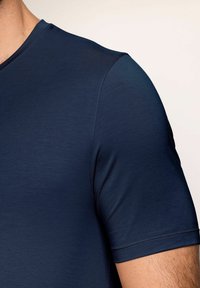 Chemise à manches courtes navy, fabriquée en tissu lisse et léger, dotée d'un col rond et de coutures discrètes le long des manches.