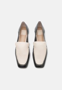 Melnas un krēmkrāsas ādas loafers ar kvadrātu formas purngalu, ar kontrastējošu šuvumu un gludu, pulētu tekstūru.
