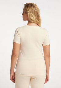 Hellbeige, figurbetontes Hemd mit kurzen Ärmeln und rundem Ausschnitt, aus glattem Stoff gefertigt, zeigt ein schlichtes Design und eine nahtlose Rückseite.