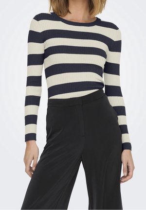 Langarmshirt aus geripptem Stoff mit horizontalen Streifen in Navy und Creme. Kombiniert mit schwarzen, hoch taillierten Hosen.