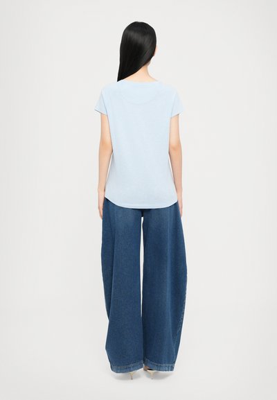 Light blue short-sleeve top with a rounded neckline, paired with wide-leg dark blue denim pants, featuring a smooth texture and subtle stitching.