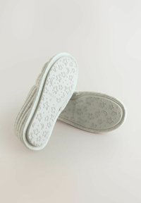 Lys grå hjemmesko med en struktureret, ribbet overdeli og en mønstret gummisål med stjerner og måner. Blød, polstret design.