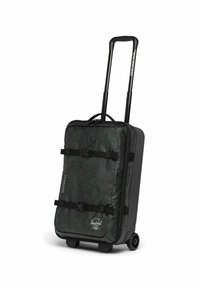 Valise à roulettes avec un tissu à motifs de feuilles noir et vert foncé, dotée de doubles poignées, d'une fermeture éclair et de sangles réglables pour sécuriser son contenu.