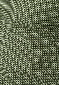 Texturiertem Stoff mit einem kleinen, sich wiederholenden, dreieckigen Muster in Grün und Schwarz, mit einer weichen Erscheinung und leichtem Stretch.