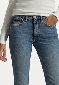 Sittande blå jeans i ljus tvättat denim, med en klassisk femficksdesign, knäppning och synliga söm detaljer.