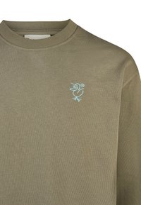 Olivenfarbener Pullover mit geripptem Rundhalsausschnitt, mit einer kleinen blauen Cartoon-Vogel-Stickerei auf der linken Brust. Glatte Textur, lässiges Design.