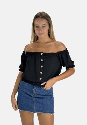 Schwarzes Oberteil mit schulterfreiem Design und elastischen Bündchen, mit einer Knopfdetailleiste an der Vorderseite. Kombiniert mit einem blauen Jeans-Minirock.