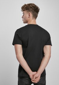 Czarny bawełniany t-shirt z krótkim rękawem i okrągłym dekoltem, charakteryzujący się gładką fakturą i luźnym krojem.
