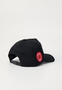 Schwarze Kappe mit gebogenem Schirm und verstellbarem Riemen, mit einem roten runden Patch, das einBull-Logo und den Text "CHICAGO BULLS" zeigt.