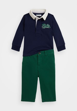 Mornarska polo majica dugih rukava s kremastim ovratnikom i zelenim logotipom "Polo Ralph Lauren", u kombinaciji sa zelenim pamučnim hlačama s kopčanjem na dugme.