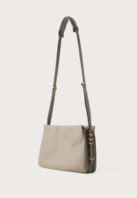 Beige rechteckige Schultertasche mit verstellbarem dunkelgrauem Tragegurt und goldfarbenen Beschlägen, vor einem schlichten weißen Hintergrund dargestellt.