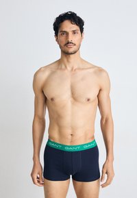 Marineblå boxerbriefs med en grønn GANT-logo i livet. Laget av et glatt strekkstoff, med en tettsittende design og midt på låret lengde.