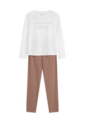Biała koszula z długim rękawem z napisem "Tylko dobre wibracje", w połączeniu z jasnobrązowymi dopasowanymi spodniami, wykonanymi z miękkiego, gładkiego materiału.