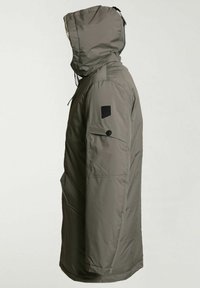 Mannequin portant un long parka à capuche vert olive avec une poche à boutons sur le bras gauche et un écusson noir au-dessus de la poche, face à droite.