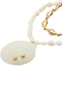 Naszyjnik z wisiorkiem w kształcie białej muszli z złotymi akcentami. Posiada okrągłe koraliki i teksturowane ogniwa, łącząc gładkie i błyszczące powierzchnie.
