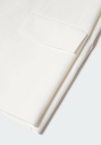 Složená bílá látka s hladkou texturou. Má přímý okraj a rovný, ostrý záhyb. Žádné vzory ani kovové části nejsou viditelné.