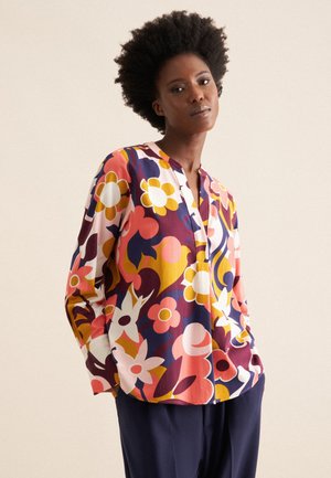 Multicolored, floral-patterned blouse with a V-neck, long sleeves, and a loose fit. Made from lightweight fabric in shades of pink, yellow, and purple.