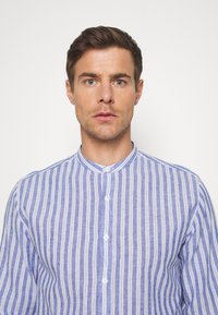 Button-up shirt featuring vertical blue and white stripes, a band collar, and lightweight fabric with a slightly textured finish.
