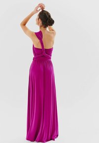 Fuchsiová maxi šaty s uzlovým designem na zádech, jedním ramínkem a hladkým materiálem vytvářejícím splývavý siluetu.