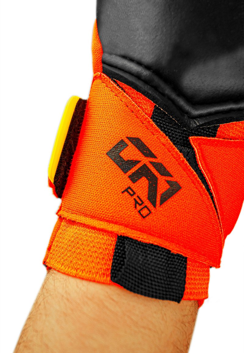 Soutien de poignet orange vif avec des accents noirs, comportant un tissu texturé, un logo et une fermeture Velcro réglable pour un ajustement sécurisé.