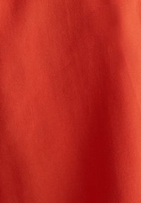 Texturovaná látka v živé červené barvě, s hladkým povrchem a mírným leskem a konzistentním vzorem.