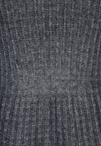 Tessuto grigio lavorato a maglia con un motivo testurizzato caratterizzato da strisce verticali. Il materiale sembra morbido con una leggera lucentezza e un design a maglia stretta.