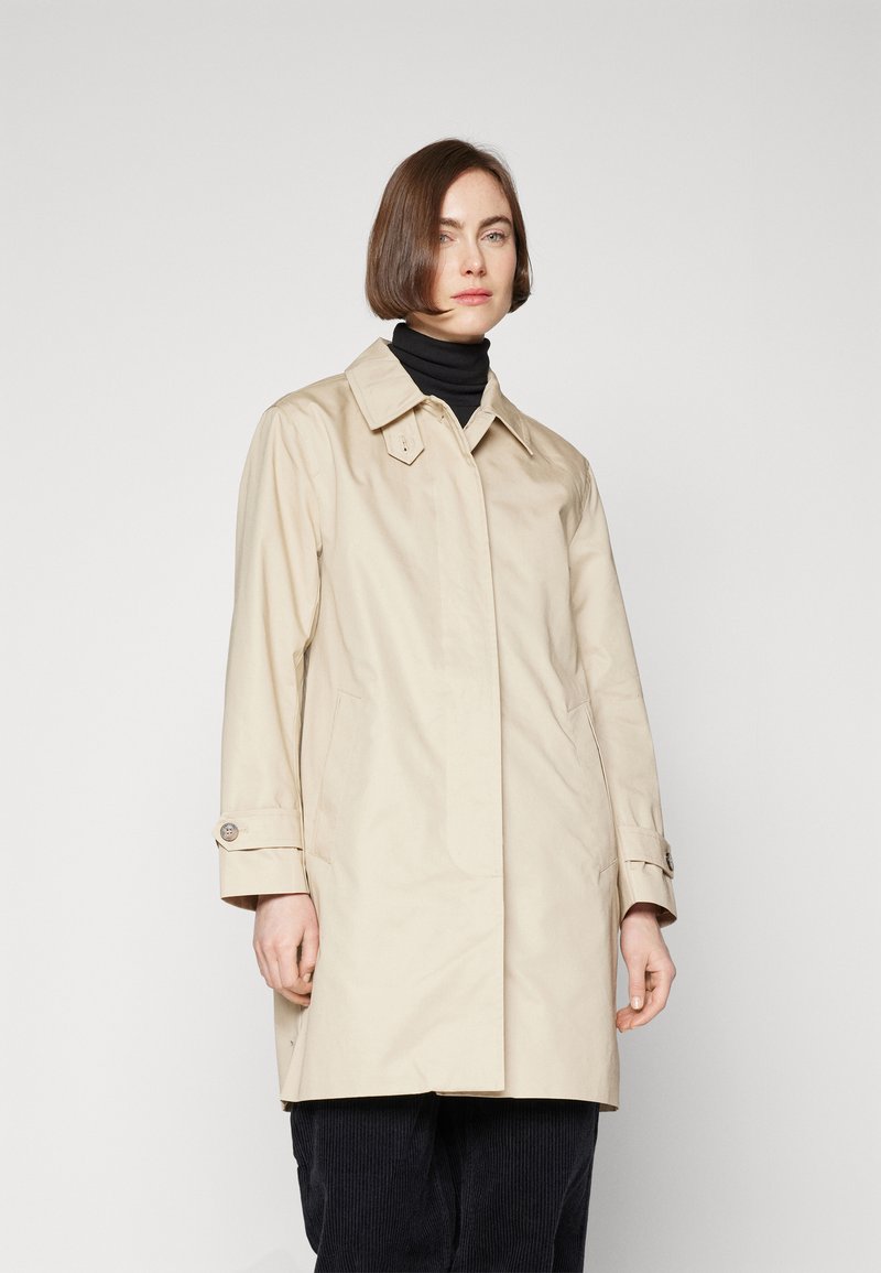 Gabardina impermeable beige con cuello puntiagudo, bolsillos laterales y puños abotonados. Textura suave y silueta entallada.