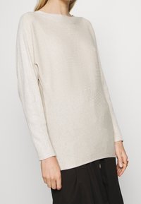 Hellbeige, gerippter Strickpullover mit einem Boot-ausschnitt und langen Ärmeln. Er hat einen lässigen Schnitt und einen leicht geschwungenen Saum.