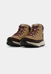 Botas de senderismo marrones con una mezcla de materiales lisos y texturizados, cordones color burdeos, puntera reforzada y suela exterior de goma negra resistente.