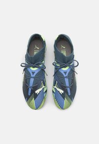 Scarpe sportive blu e verdi con tomaia in tessuto texturizzato, design angolare e pattern a contrasto. Lacci e logo sul tallone.