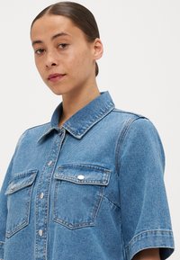 Helles blaues Denimhemd mit kurzen Ärmeln, großen Vordertaschen, Knopfverschlüssen und klassischem Kragen. Verfügt über eine strukturierte Passform und klare Linien.