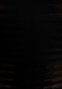 Un indumento nero con strisce verticali texture e una superficie di tessuto liscia, con una cucitura che corre verticalmente al centro.