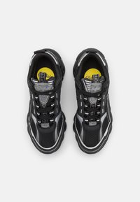 Black and grey athletic shoes with a mesh upper, rubber soles, reflective stripes, and a prominent yellow insole.