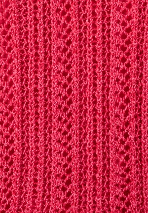 Tissu tricoté rouge montrant un motif de dentelle détaillé avec des bandes verticales et de petits trous ouverts.