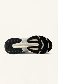 Scarpa da atletica leggera con una suola in gomma nera flessibile, una intersuola bianca texturizzata e rinforzi per la durata.