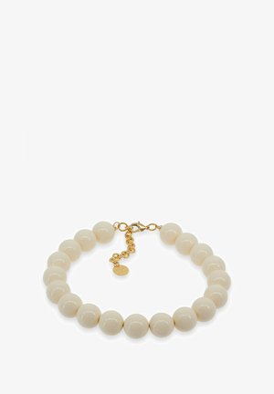 Bransoletka z okrągłych kremowych koralików z zapięciem typu homar w kolorze złotym oraz regulowanym łańcuszkiem na białym tle.