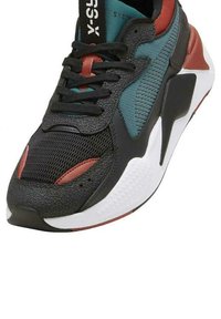 Zwarte sneaker van gestructureerd leer en mesh. Heeft details in teal en rood, veters, een gevoerde kraag en een witte rubberen zool met grip.
