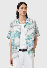 Camisa de manga corta, con botones, en tejido ligero, que presenta un estampado de paisaje tropical en tonos verdes, azules y rosas, con un bolsillo delantero.