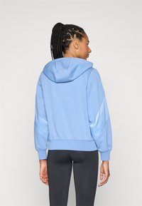 Sweatshirt com capuz azul claro, em tecido texturizado com detalhes em cetim nas mangas, punhos canelados e bainha. Apresenta um corte descontraído.