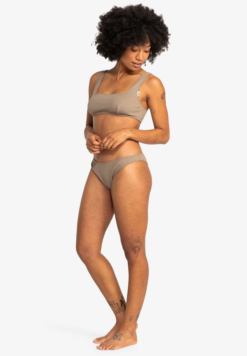 Brown ribbed bikini set featuring a one-shoulder top and matching bottoms. Soft texture, seamless design, and minimalistic style.
